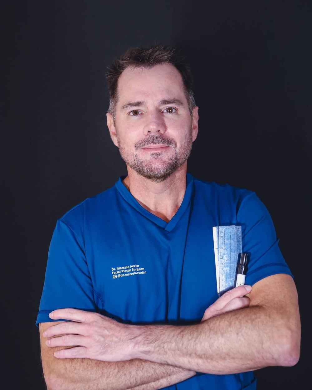 Dr. Marcelo Avelar em traje cirúrgico, com régua de marcação